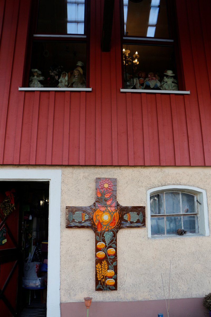 2022_04_ausstellung (02).jpg - Kreuz aus Tontafeln am Eingang zur Museumsscheune - ursprünglich entstanden als Fronleichnamsdekoration für ein Pfarrhaus - 5 Brote und 2 Fische - Ähren und Weintrauben